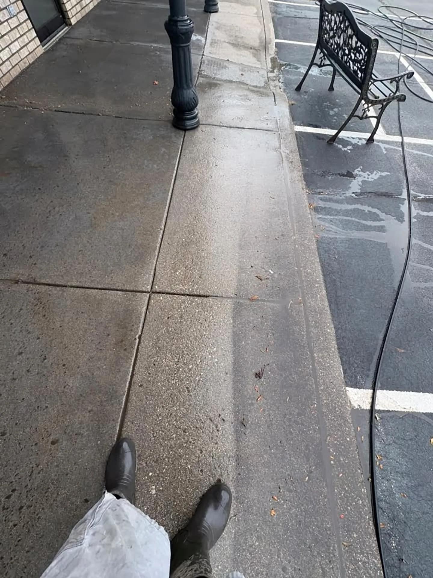 Concrete walkway mid-wash, a clean strip cut through grey surface grime