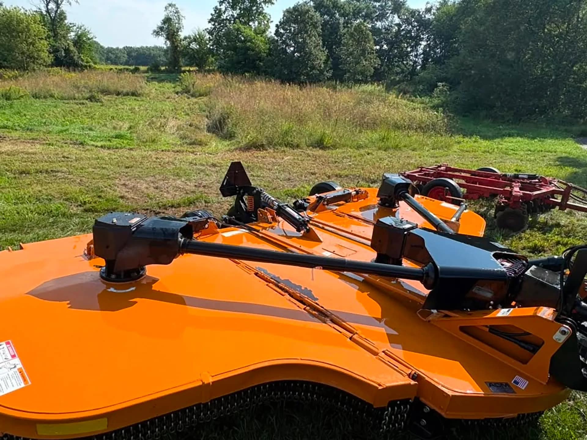 Orange rotary mower deck cleaned of caked grass and mud