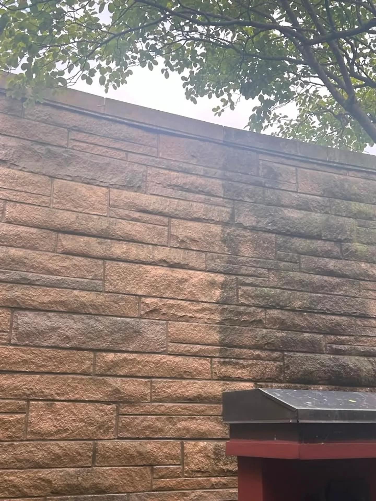 Block retaining wall with the washed section noticeably lighter than the weathered one
