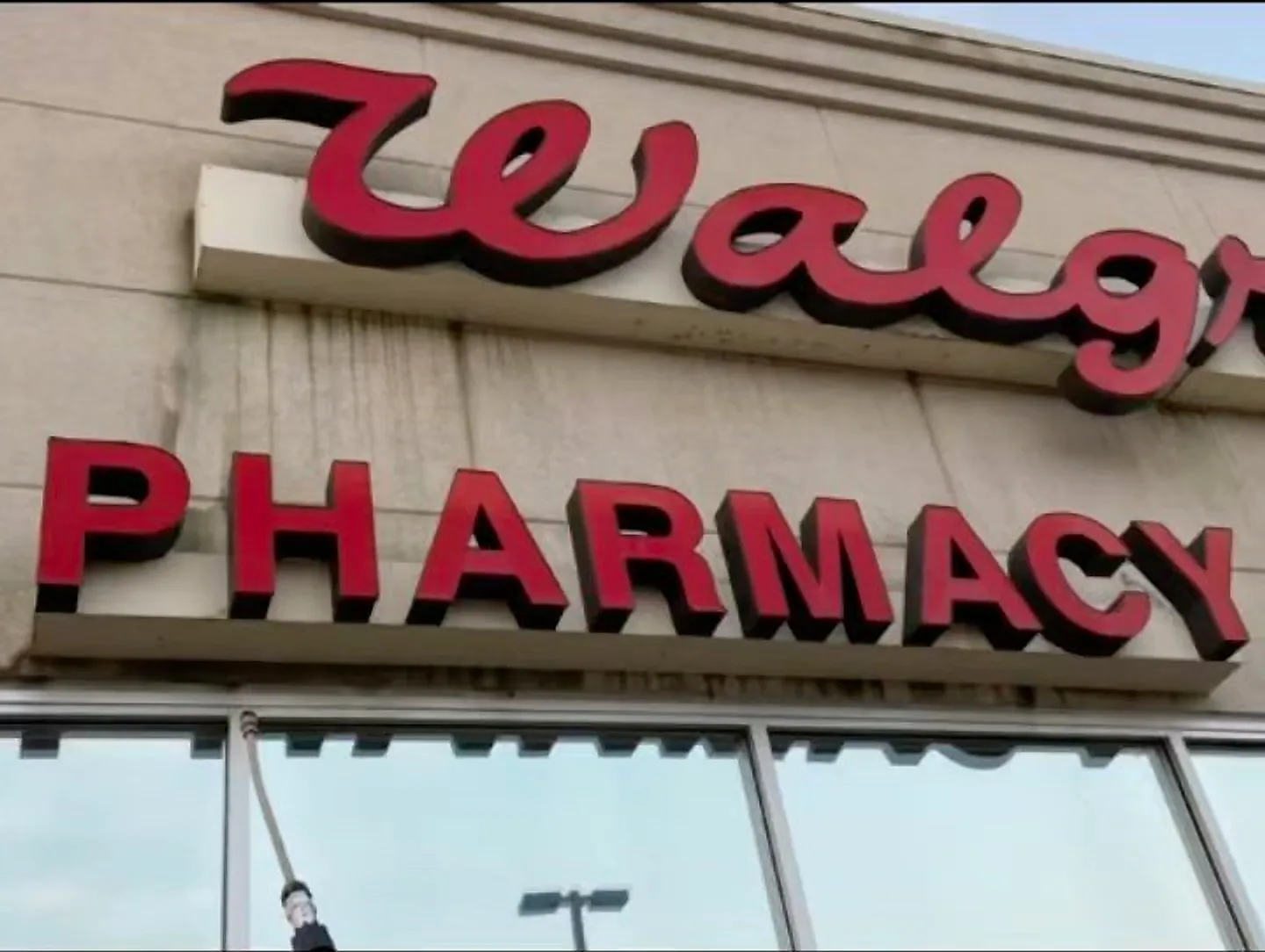 The Walgreens pharmacy sign and fascia being washed, wand and spray in frame